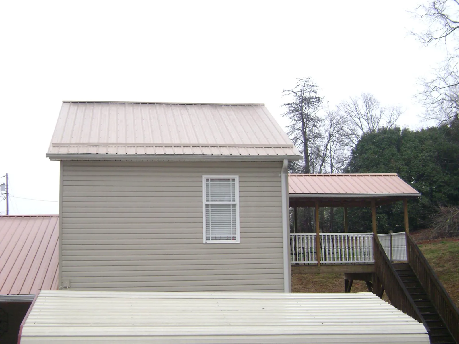 Tan metal roofs on a two story addition and attached porch, from a Roof Replacement job in Union City